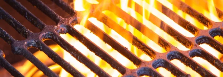 Nahaufnahme eines heißen Grillrosts, durch den Flammen schlagen.